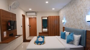 A hotel room with a bed, a TV, a fan, and a mirror. - Visthara Elite (Bengaluru)