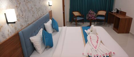 A hotel room with a bed, two chairs, a desk, and a window with curtains.