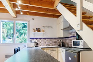 Una cocina con encimera de granito, armarios blancos, microondas y horno empotrado.