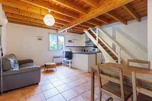 Et moderne interiør med træloft, en sofa, et spisebord og et køkken.