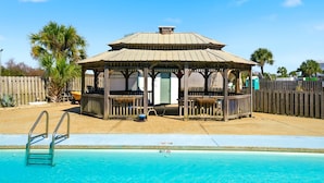 Una pérgola con una piscina al frente.