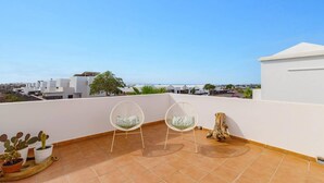 A rooftop terrace with two white chairs, a cactus plant, and a tree stump. - Villa Sapri by Villa Plus (Playa Blanca)