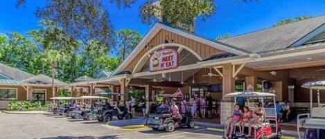A restaurant with a 'Meet N Eat' sign, outdoor seating, and golf carts.