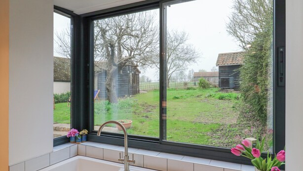 Eine Küche mit Fenster, Spüle und Blumen in einer Vase.