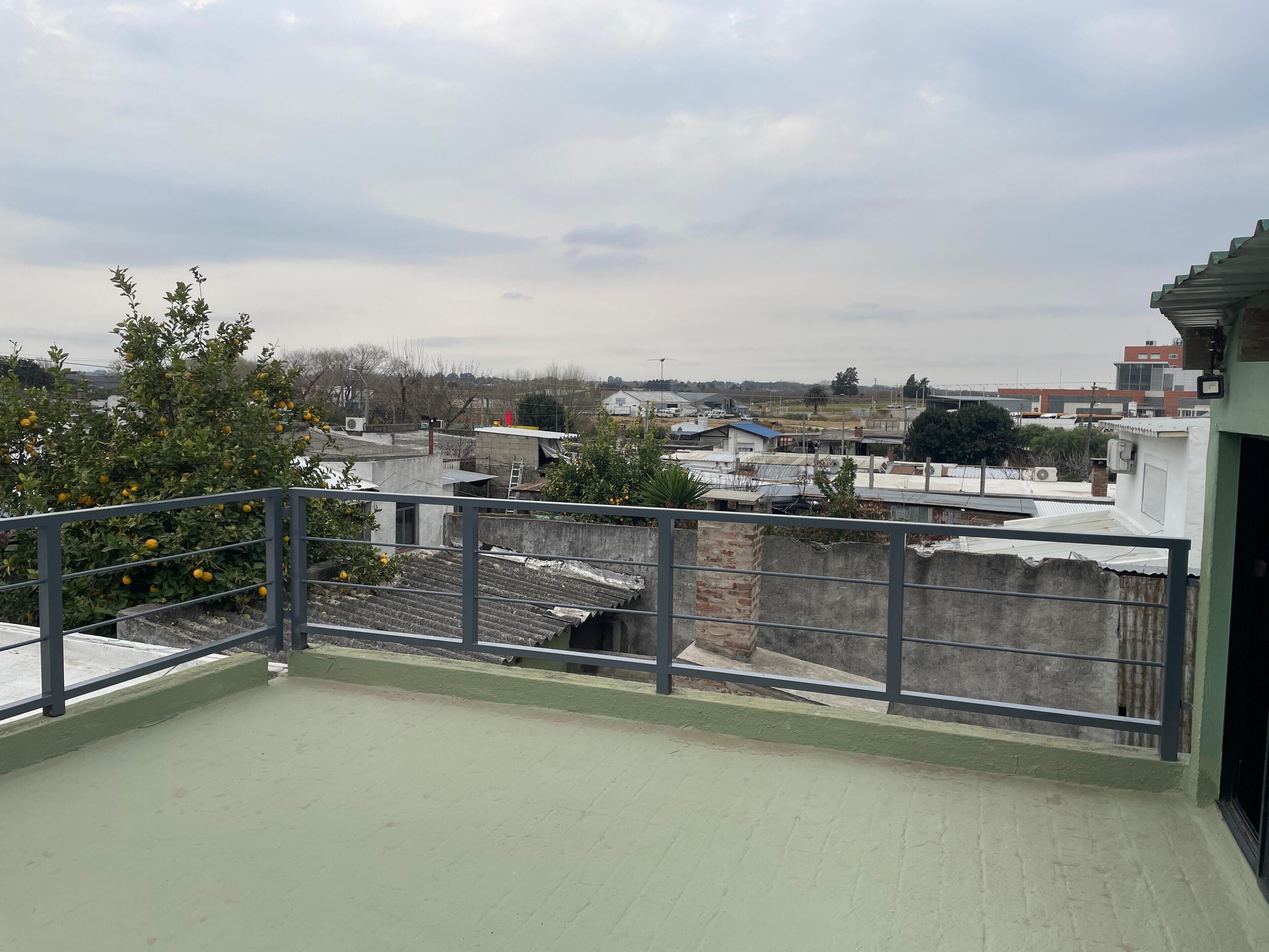 Eine Dachterrasse mit Blick auf umliegende Gebäude und einen Baum mit gelben Früchten.