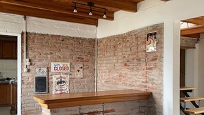 A bar area with a brick wall, wooden ceiling, and metal bar stools.