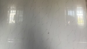 Un chauffe-eau blanc, fixé au plafond, doté d’un panneau de commande et d’un tuyau flexible.