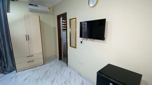 Une chambre avec une armoire, un téléviseur fixé au mur et une horloge.