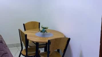 A small dining area with a wooden table and chairs, a painting on the wall, and a brown sofa.