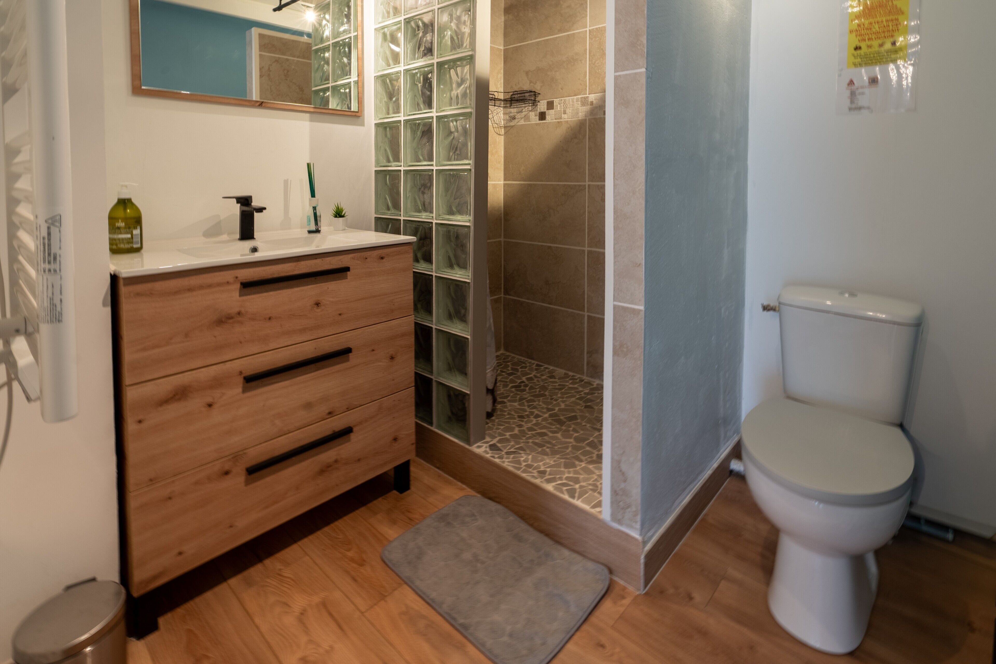 A bathroom with a wooden vanity, a glass shower enclosure, and a toilet.