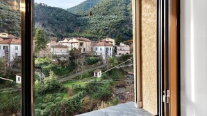 Vista desde una ventana sobre una colina con edificios, una carretera y vegetación.
