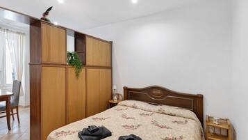 Une chambre à coucher avec un lit, une armoire en bois, une petite table avec une lampe et une chaise.