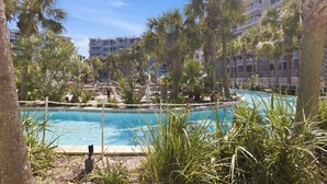 Una piscina circondata da palme e un edificio con balconi.