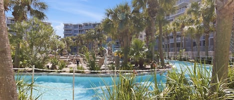 A pool surrounded by palm trees and a building with balconies.