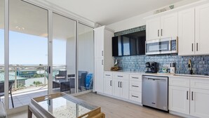 Una cucina moderna con mobili bianchi, una lavastoviglie in acciaio inossidabile e un'ampia finestra con vista su un balcone.