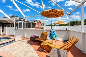A covered outdoor area with lounge chairs, a pool, and umbrellas. - CASA KAMPA offers you a heated pool with Jacuzzi at no additional cost. (Tampa)