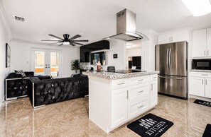 A modern kitchen with a central island, stainless steel appliances, and a ceiling fan. - CASA KAMPA offers you a heated pool with Jacuzzi at no additional cost. (Tampa)