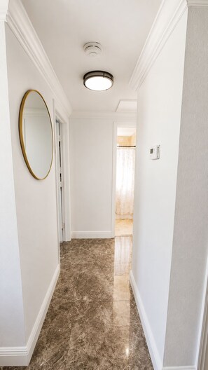 A hallway with a marble floor, a round mirror, and a ceiling light fixture. - CASA KAMPA offers you a heated pool with Jacuzzi at no additional cost. (Tampa)