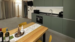 Uma cozinha moderna com armários verdes, uma mesa de jantar de madeira e uma cadeira amarela.