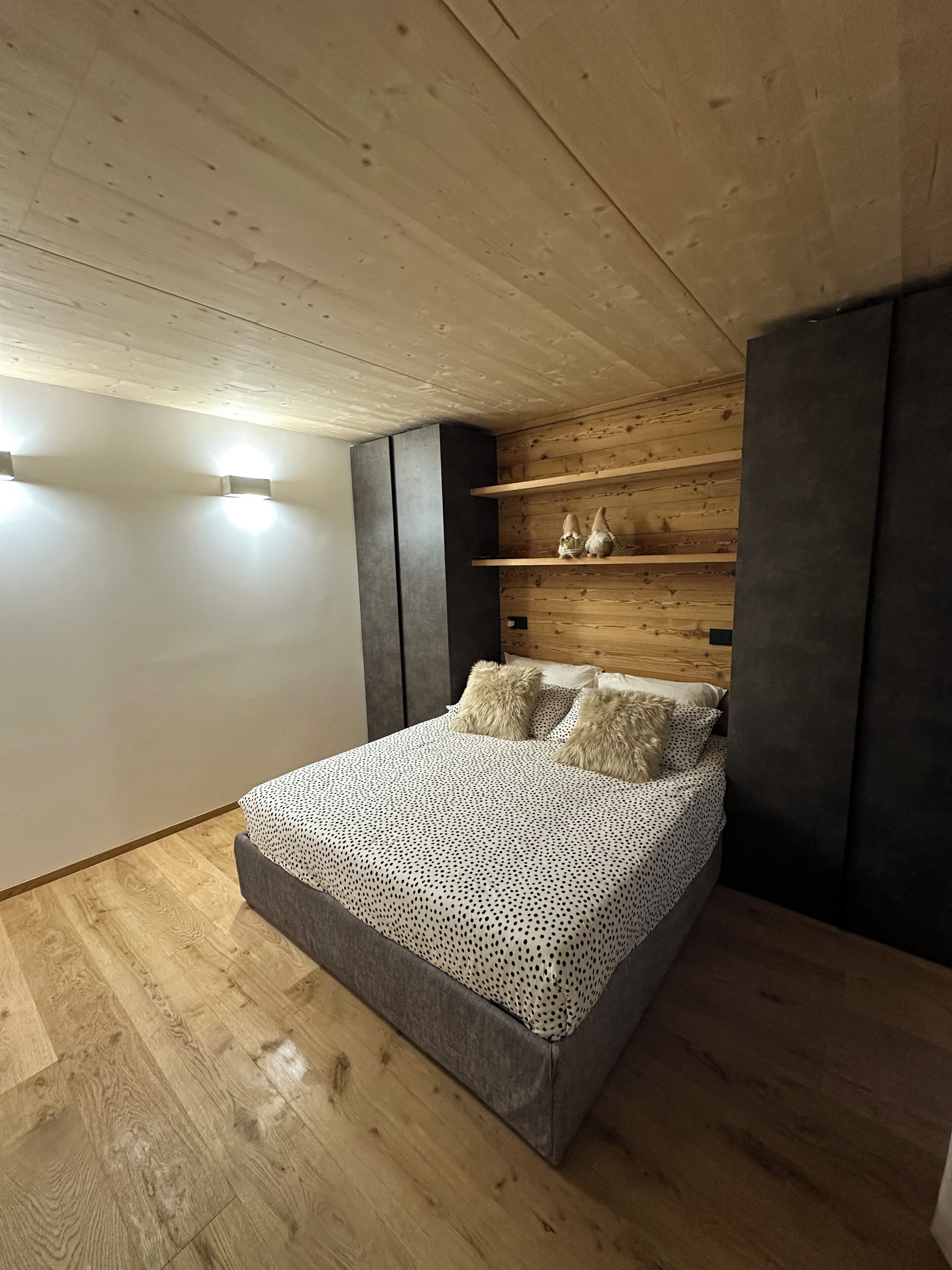 Une chambre à coucher avec un lit, un plancher en bois et un plafond en pente.