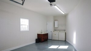 A small, clean room with a white sink, a wooden cabinet, and a washing machine. - Pine Ridge Getaway (Fort Payne)