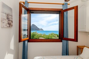 A room with a large window, a bed, and a wall-mounted picture.