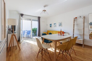 Una sala de estar moderna con una mesa de comedor, sillas, un sofá y un balcón con vistas.