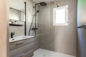 Un baño moderno con ducha, lavabo y espejo.