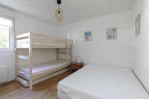 A room with a bunk bed, a single bed, a small wooden nightstand, a wall-mounted light fixture, and two framed pictures. - Vacation Home 'Villa du Lac - Souston Plage' with Shared Pool - Conciergerieland (Soustons)