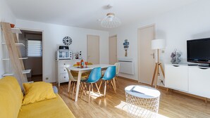 A compact living space with a dining area, kitchenette, and a television.