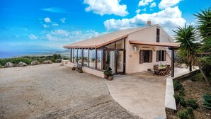 Una casa amb un patio, una zona de menjador i vistes al mar.