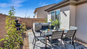 Une terrasse extérieure avec une table et des chaises, un jacuzzi et un barbecue.