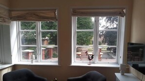 Une pièce comprenant deux fauteuils, une petite table avec un vase et un téléviseur posé sur une commode.