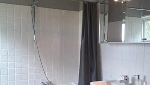 Une salle de bain moderne équipée d’une baignoire, d’une douche et d’un meuble-lavabo avec un miroir et un évier.