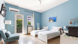 A bedroom with two beds, a sofa, a TV, and a balcony. - Il Geosito - Camera tripla (Gallipoli)