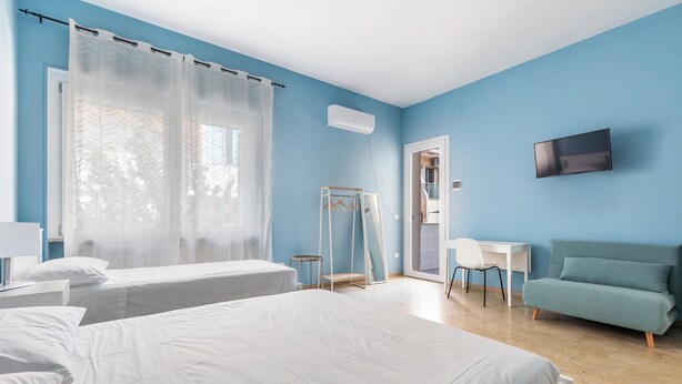 Une chambre d’hôtel avec deux lits, une télévision, un bureau, une chaise et un canapé.