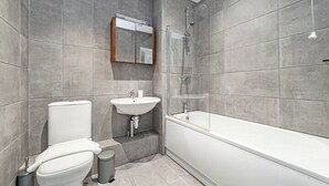 A modern bathroom with a toilet, sink, and bathtub. - Comfortable 2-Bed Apartment Near Brixton (London)
