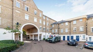 A multi-story residential building with a central courtyard, featuring a covered entrance and multiple balconies. - Comfortable 2-Bed Apartment Near Brixton (London)