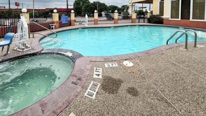 Una piscina con tabla de clavados, un jacuzzi y un letrero que indica que no se permite bucear.