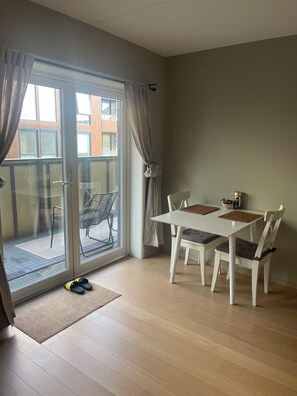 A room with a sliding glass door leading to an outdoor area, a white table with two chairs, and a small rug on the floor. - Cozy Central Apartment in Oslo - Available Feb 17 to March 8 (Oslo)