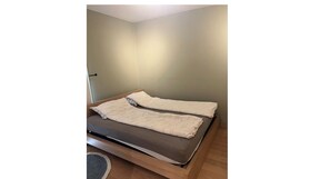 A single bed with a wooden frame and a dark mattress, covered with a white blanket and a matching pillow. - Cozy Central Apartment in Oslo - Available Feb 17 to March 8 (Oslo)