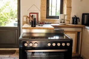Une cuisine équipée d’une cuisinière, d’une machine à café et d’une fenêtre donnant sur un paysage verdoyant.