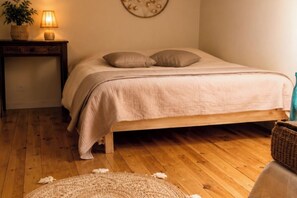 Une chambre avec un lit en bois, une lampe de chevet, un élément de décoration murale et un panier en osier.
