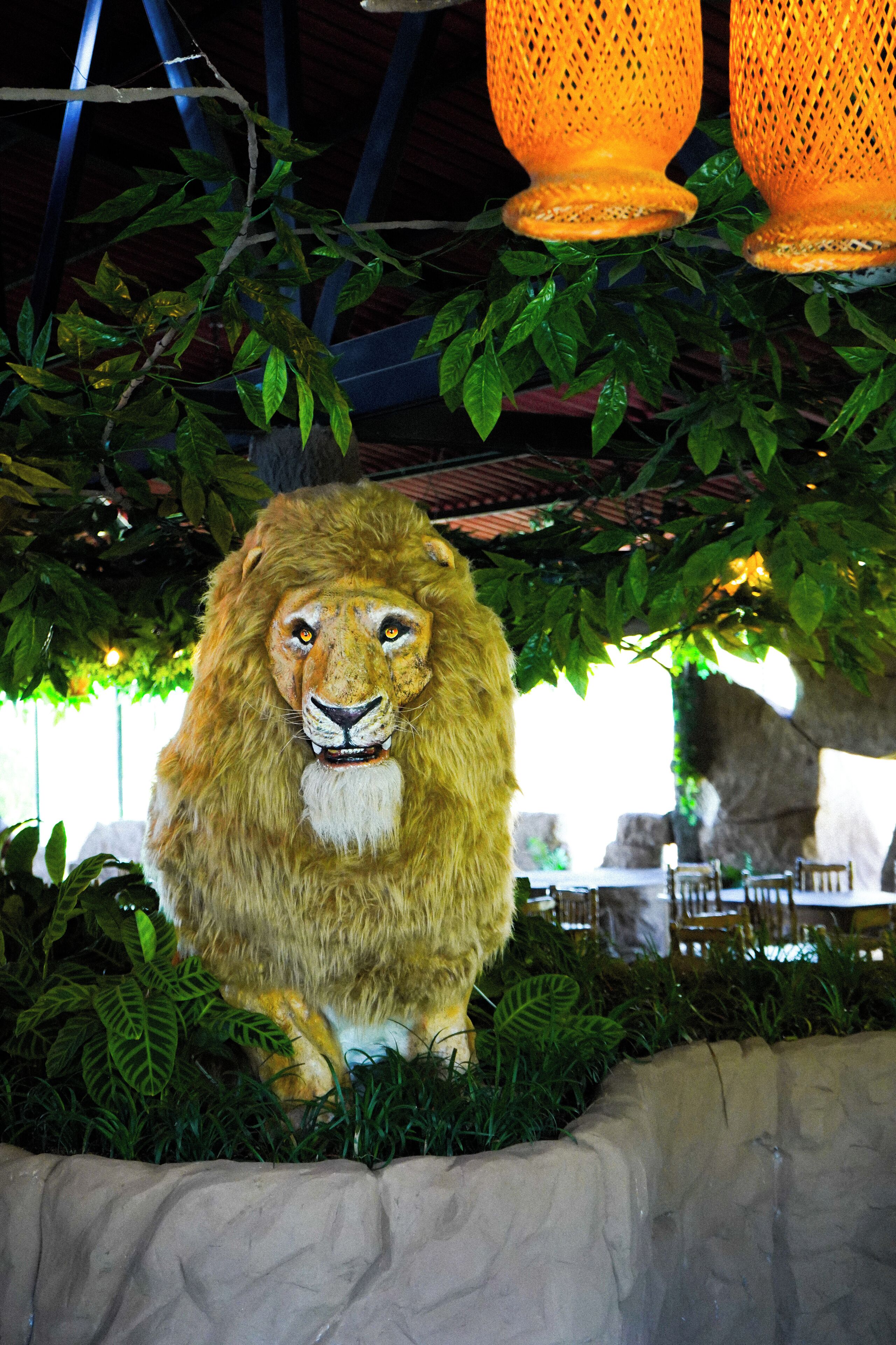 A lion statue surrounded by greenery and stone walls.