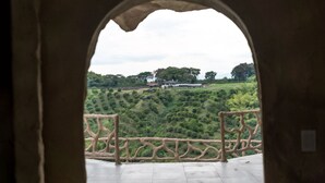 An arched doorway leading to a balcony with a view of a hilly landscape and a building in the distance. - MAHAWI RESORT (Calarca)