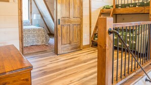 Een gezellig slaapkamer op zolder met een houten deur, een bed met beddengoed met dessin en een houten dressoir.