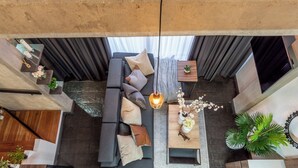 A modern living room with a grey sofa, multiple cushions, a wooden coffee table, and a hanging light fixture. - Manila Luxury Suites 401 (Medellín)