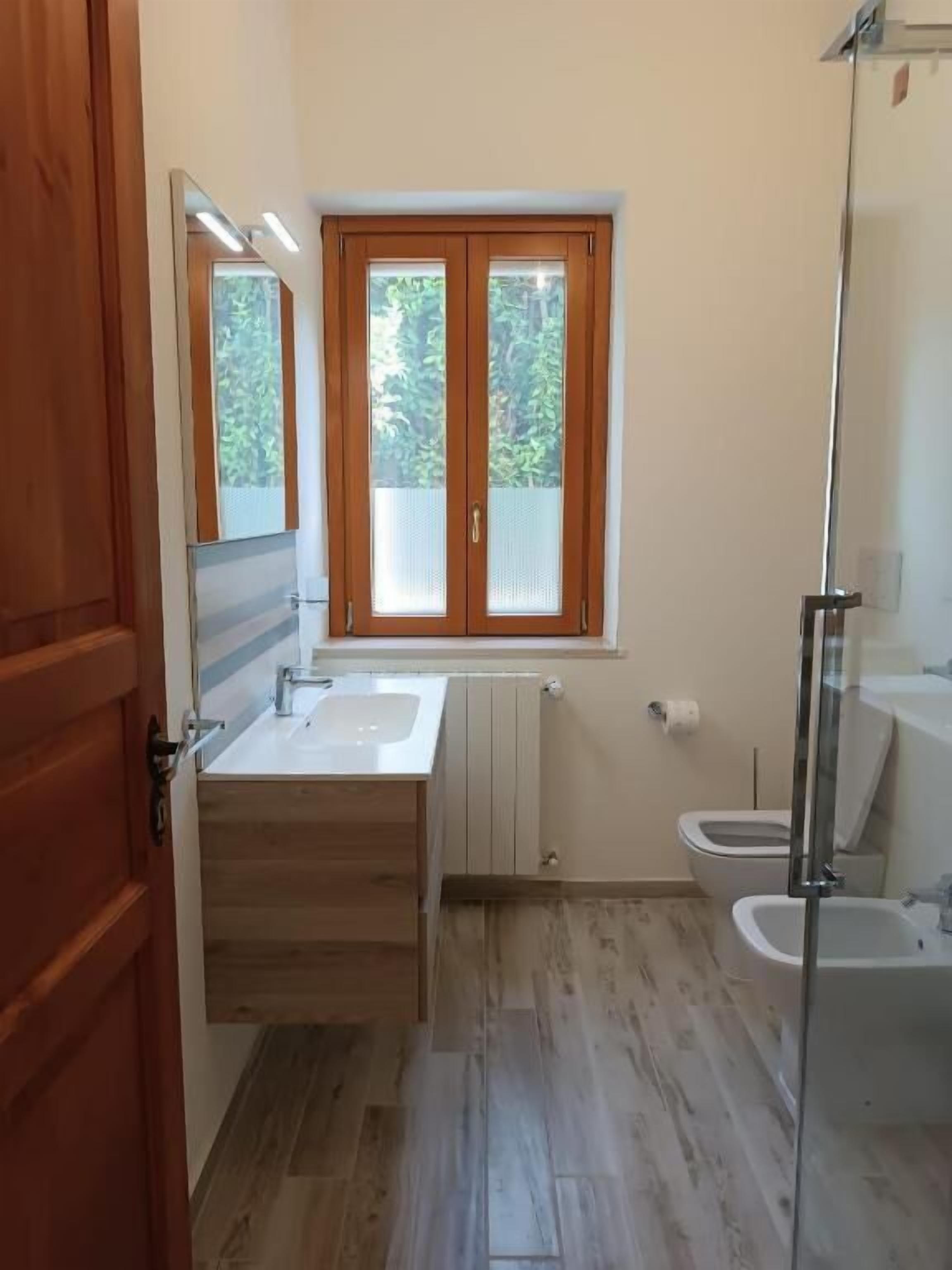 Ein Badezimmer mit einem Holzbadschränken, einem Doppelwaschbecken, einer Toilette und einer Duschkabine aus Glas.