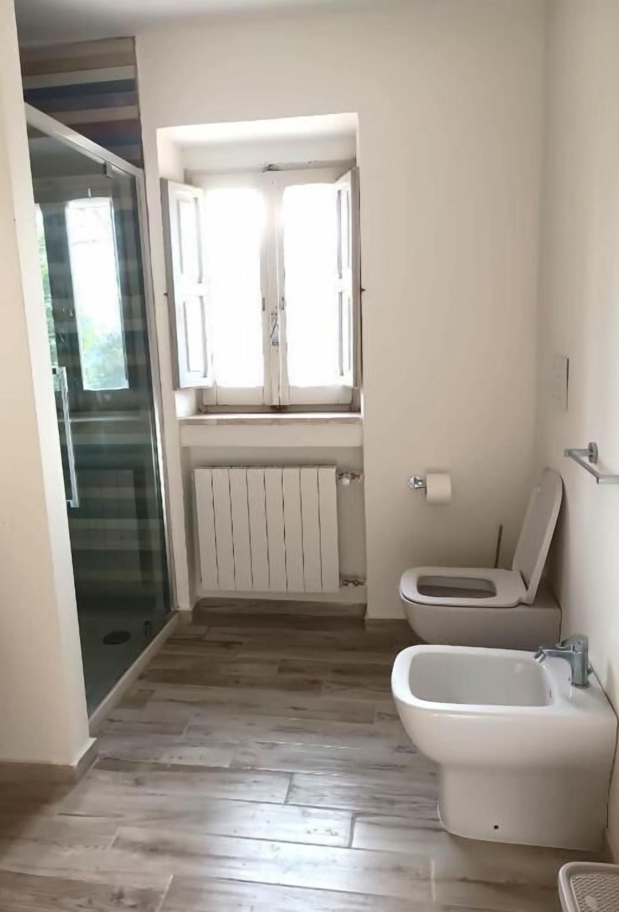 A bathroom with a toilet, bidet, and a glass shower enclosure.