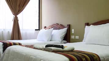 Una habitación de hotel con dos camas, una ventana con cortinas y un interruptor de pared.